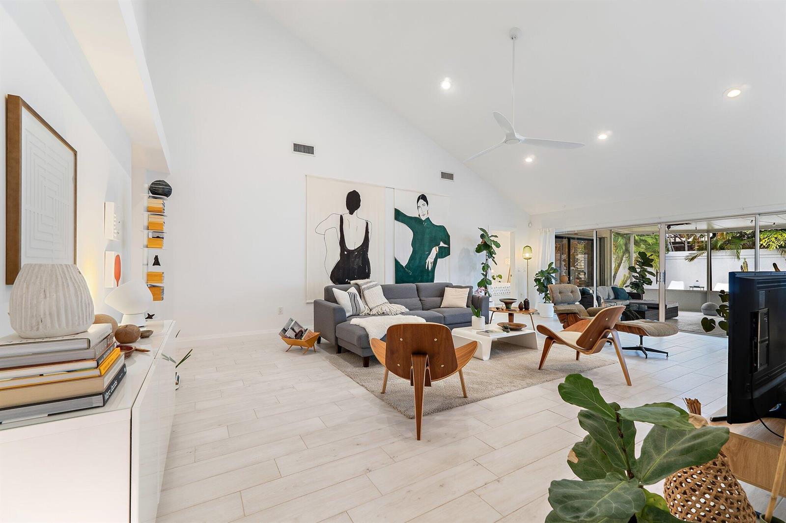 A bright living room features vaulted ceilings, white tile floors, and large abstract wall art — 125 Harbourside Circle, Jupiter FL 33477, JUPITER, FL