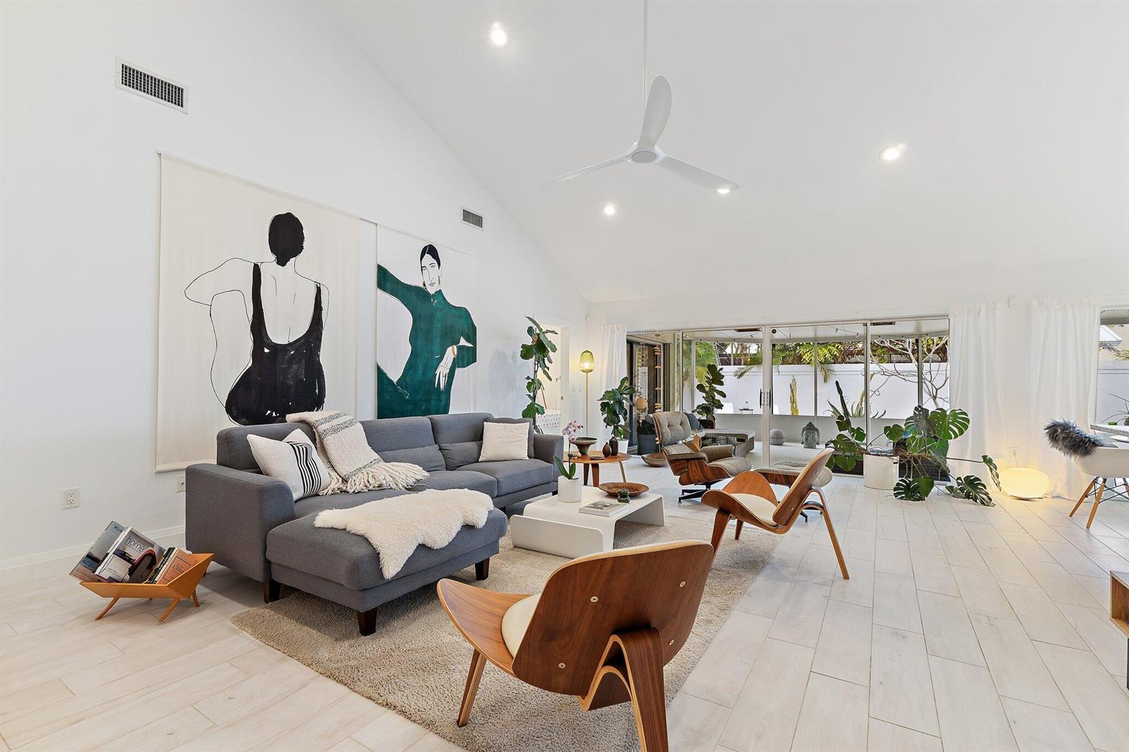 A bright living room features a vaulted ceiling, gray sectional sofa, and large wall art — 125 Harbourside Circle, Jupiter FL 33477, JUPITER, FL