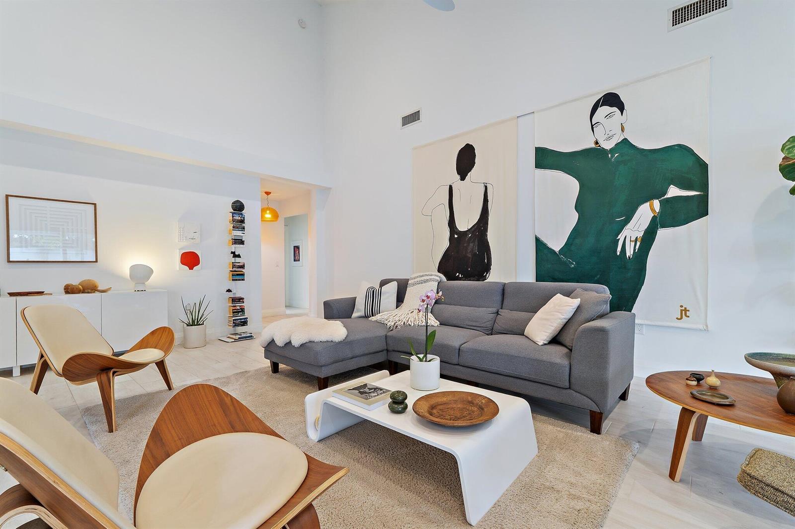A modern living room features a grey sectional sofa, two wooden chairs, and large wall art — 125 Harbourside Circle, Jupiter FL 33477, JUPITER, FL