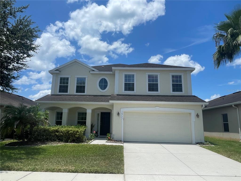 A two-story suburban house features a beige stucco exterior, a two-car garage, and a front porch — 10723 CLOVER WALK DRIVE, ORLANDO, FL