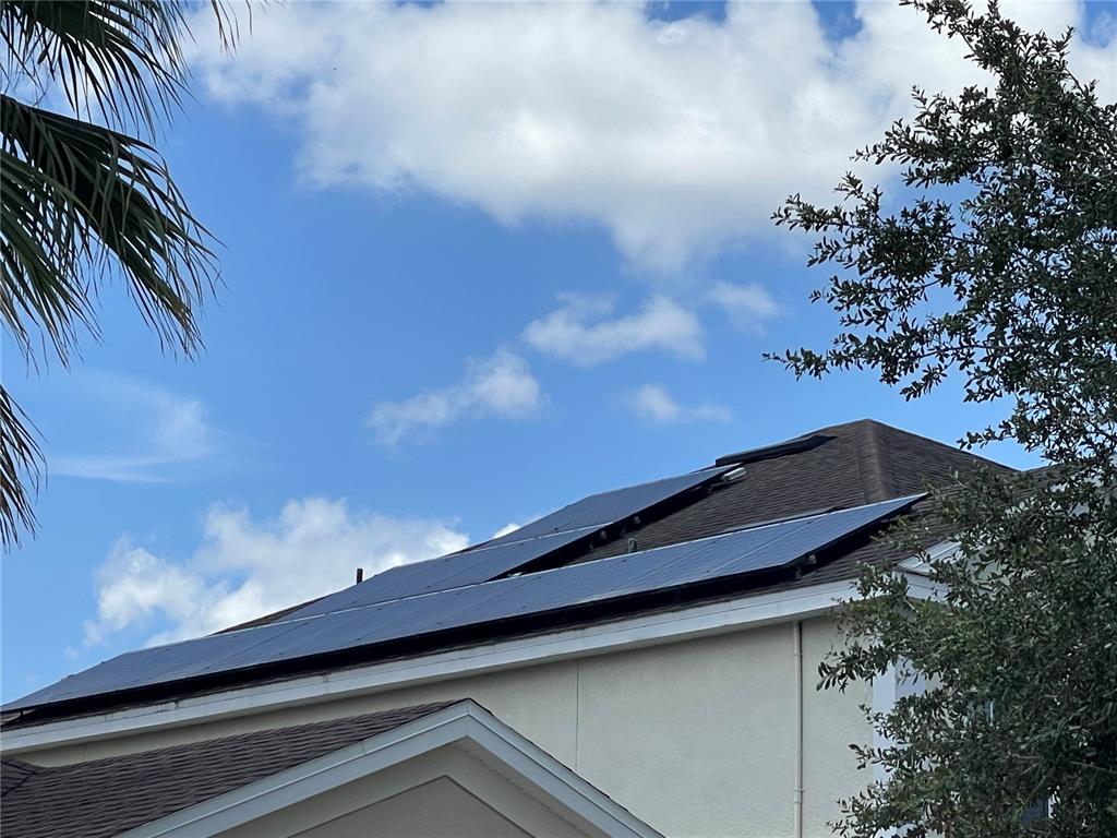 A house roof features several solar panels installed on its sloped surface — 10723 CLOVER WALK DRIVE, ORLANDO, FL