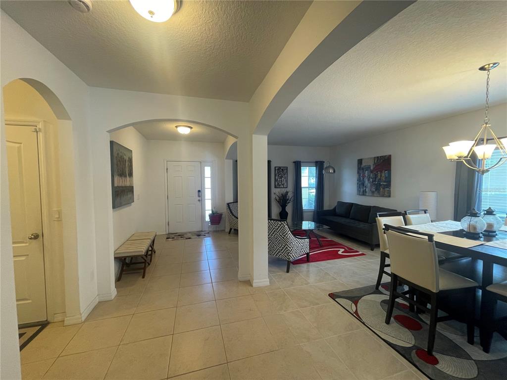 An open-concept interior features a tiled entryway, a dining area, and a living room — 10723 CLOVER WALK DRIVE, ORLANDO, FL