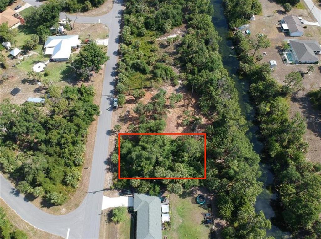 An aerial view shows a rectangular wooded lot situated between a road and a canal — 242 LONGLEY DRIVE, PORT CHARLOTTE, FL