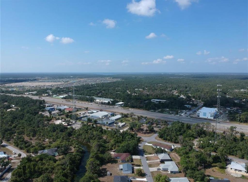 An aerial view shows a highway running through a wooded area with scattered residential buildings — 242 LONGLEY DRIVE, PORT CHARLOTTE, FL
