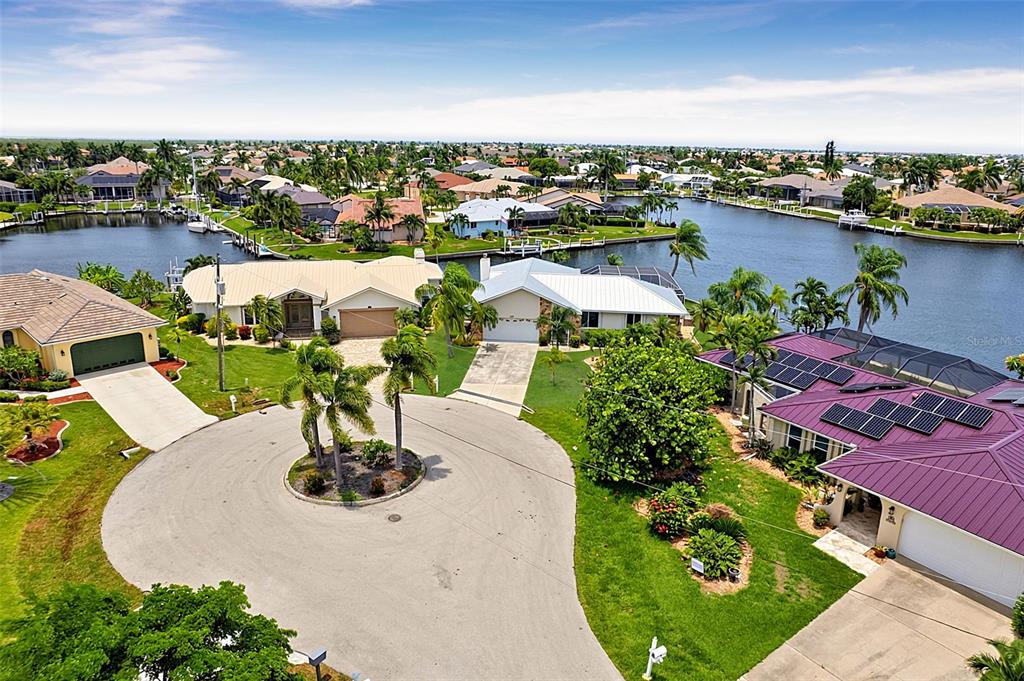 An aerial view of a residential cul-de-sac with waterfront homes and palm trees — 1230 SWAN COURT, PUNTA GORDA, FL