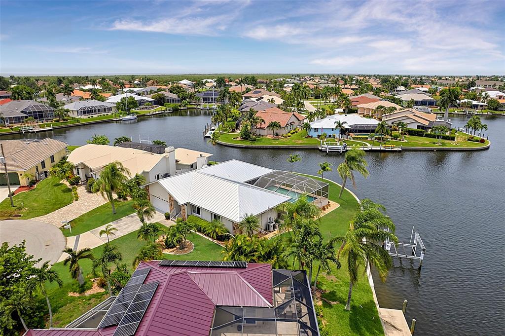 An aerial view shows waterfront houses with swimming pools and docks along a canal — 1230 SWAN COURT, PUNTA GORDA, FL