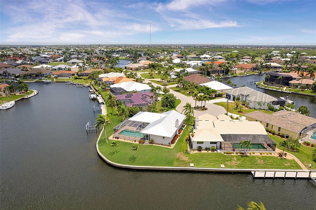 An aerial view shows waterfront homes with swimming pools and boat docks along a canal — 1230 SWAN COURT, PUNTA GORDA, FL