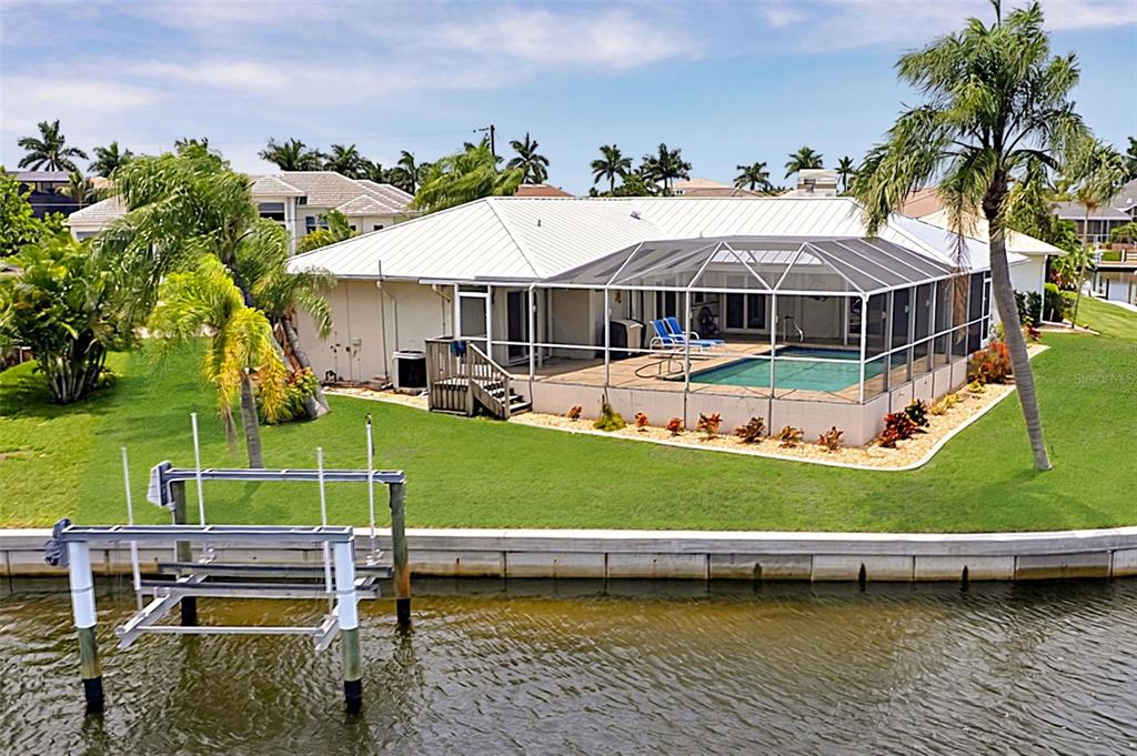 An aerial view of a waterfront house with a screened-in pool and a boat lift — 1230 SWAN COURT, PUNTA GORDA, FL