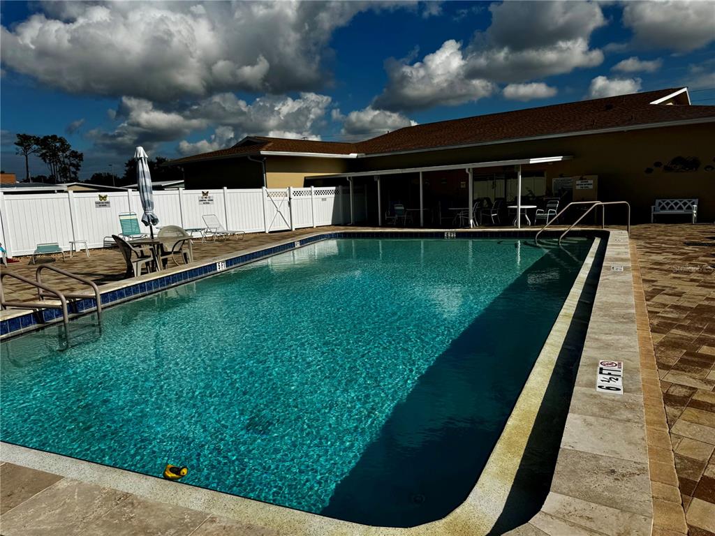 A rectangular swimming pool with a depth marker is surrounded by a paved patio area — 5619 BAYSHORE ROAD UNIT 120, PALMETTO, FL