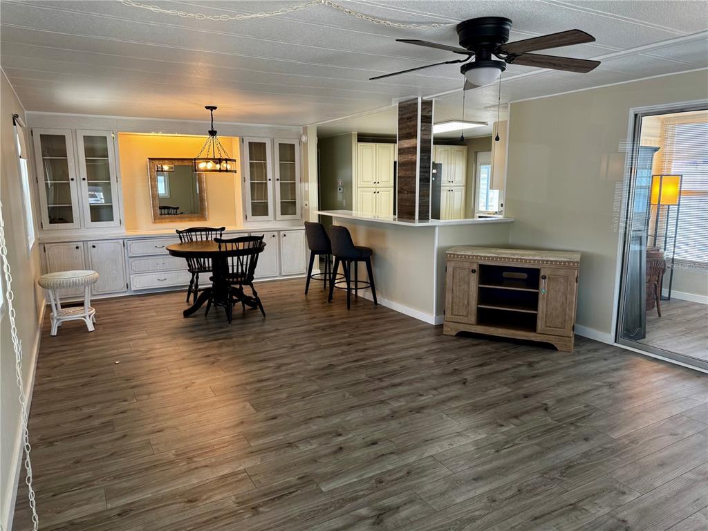 A dining area with wood-look flooring, built-in cabinetry, a breakfast bar, and a ceiling fan — 5619 BAYSHORE ROAD UNIT 120, PALMETTO, FL
