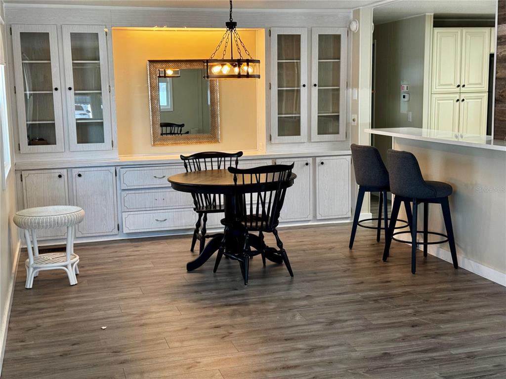 A dining area features built-in white cabinetry, a round table with chairs, and wood-look flooring — 5619 BAYSHORE ROAD UNIT 120, PALMETTO, FL
