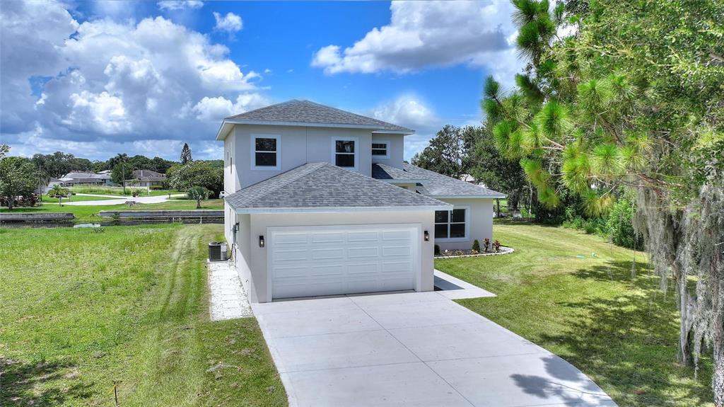 An aerial view of a two-story house with a white garage and a concrete driveway — 100 TUOMEY COURT, LAKE PLACID, FL