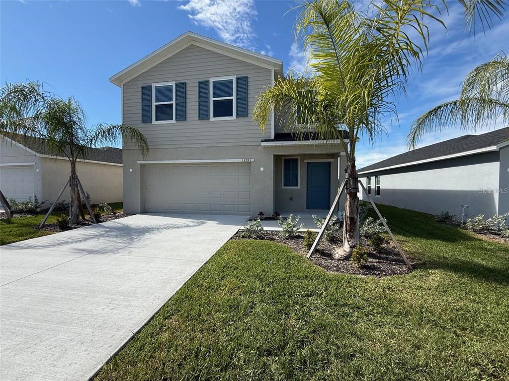 A two-story suburban house features light gray siding, a concrete driveway, and two palm trees — 11795 CLOVERLY LANE, PUNTA GORDA, FL