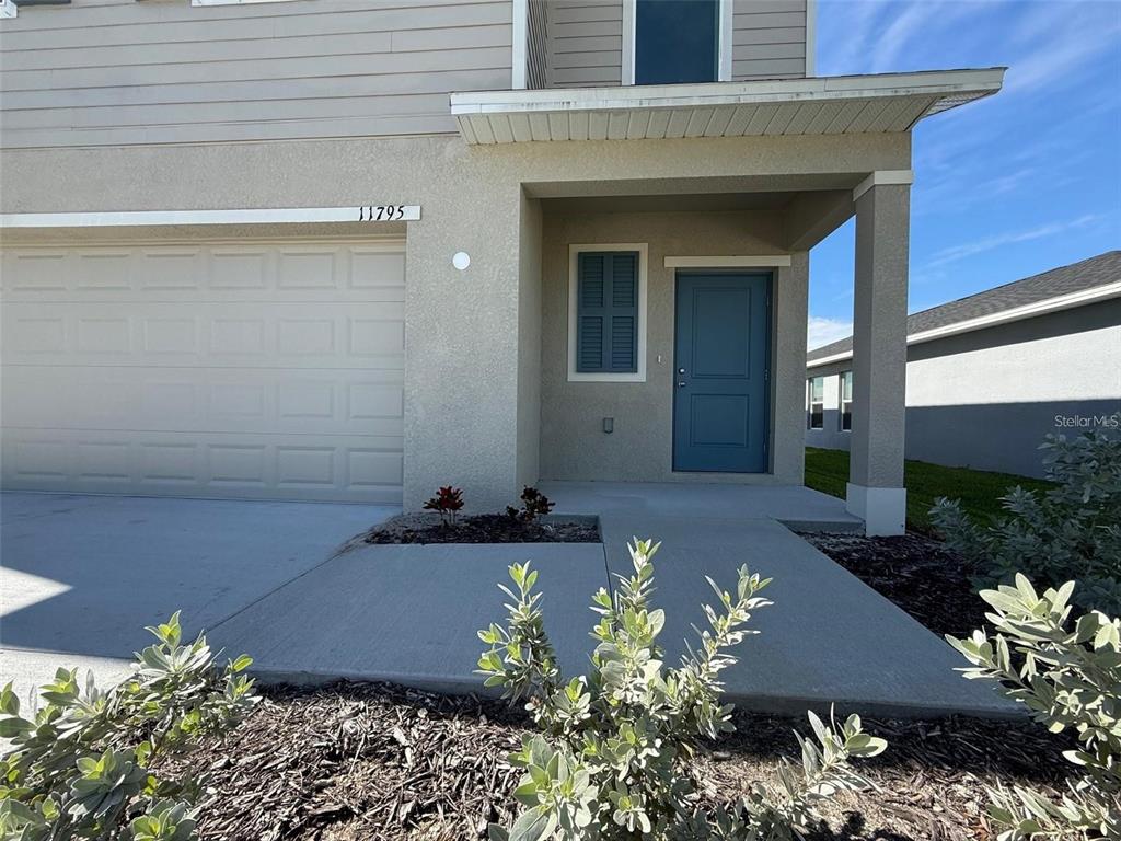 The exterior of a two-story house features a blue front door and a garage — 11795 CLOVERLY LANE, PUNTA GORDA, FL