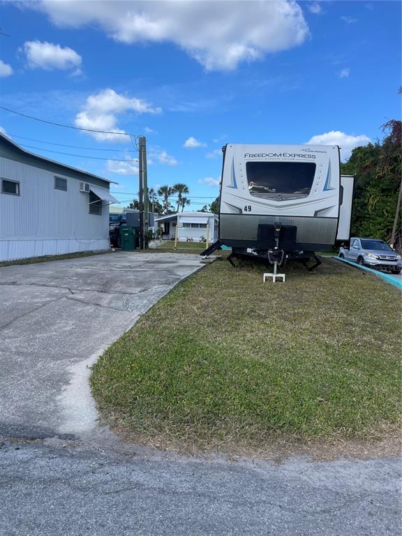A travel trailer is parked on a grassy lot next to a concrete driveway and home — 49 INDIANA STREET, PALMETTO, FL
