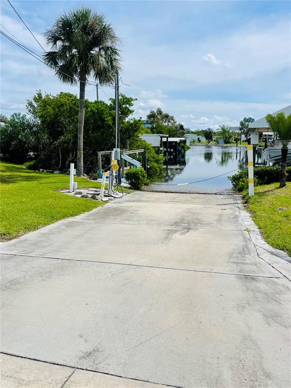 A concrete boat ramp leads into a canal lined with docks and palm trees — 49 INDIANA STREET, PALMETTO, FL