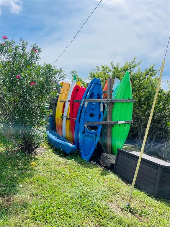 A collection of colorful kayaks is stored upright in a wooden rack outdoors — 49 INDIANA STREET, PALMETTO, FL