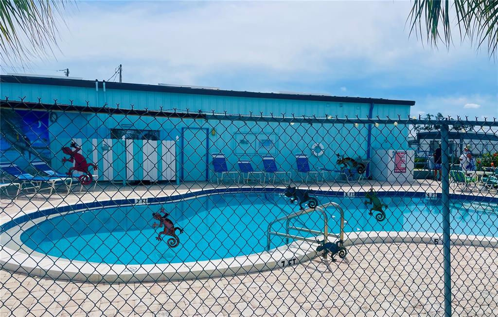 A fenced-in swimming pool sits in front of a light blue building with lounge chairs — 49 INDIANA STREET, PALMETTO, FL