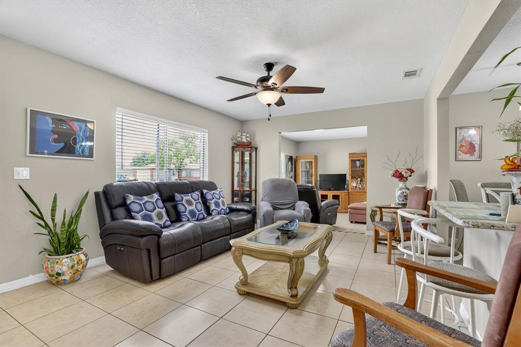 A living room with tile flooring, a dark leather sofa, and a ceiling fan — 3804 JANIE COURT, ORLANDO, FL