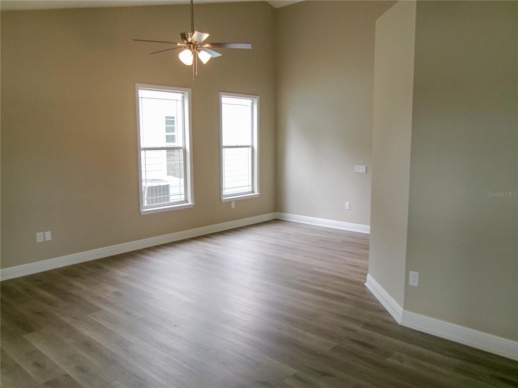 An empty room features light-colored walls, wood-look flooring, two windows, and a ceiling fan — 37450 PICKETTS MILL AVENUE, ZEPHYRHILLS, FL