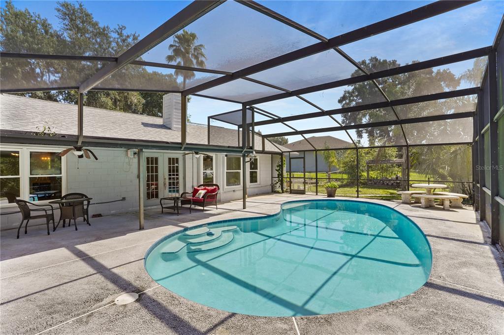 A swimming pool sits on a concrete patio enclosed by a screened-in lanai — 515 CLOUDCROFT DRIVE, DELTONA, FL