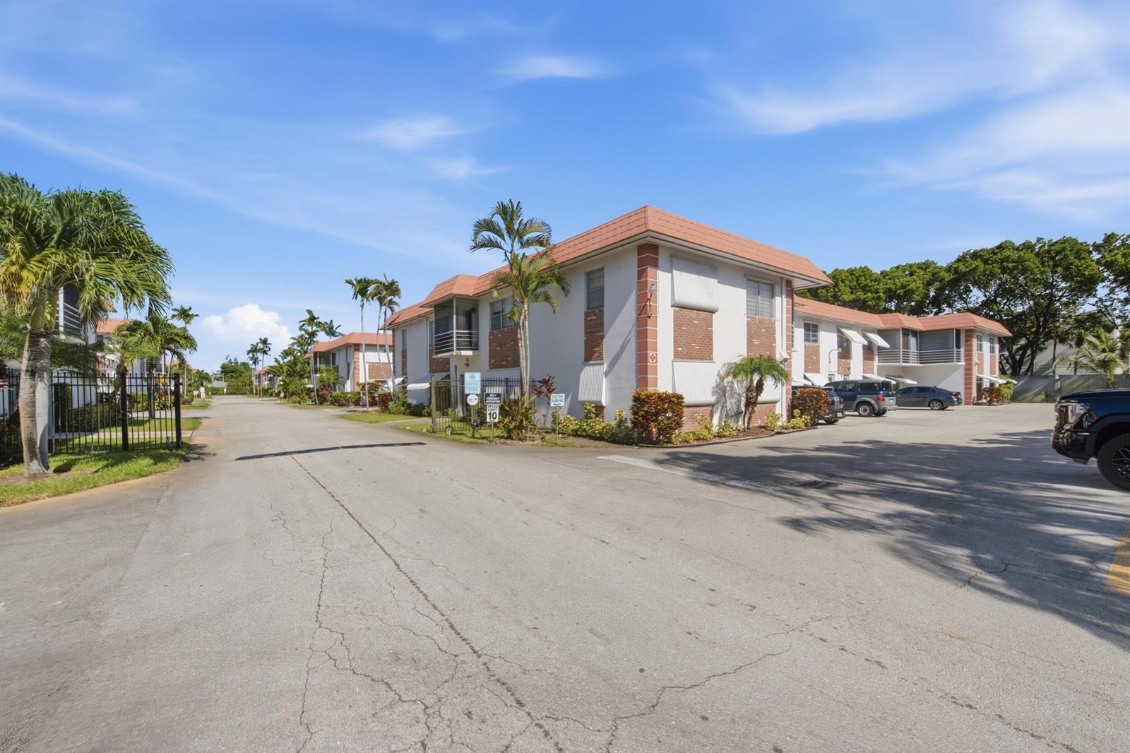 An exterior view of a multi-story apartment complex with palm trees and a parking lot — 3550 NW 8th Avenue # 812, Pompano Beach FL 33064, POMPANO BEACH, FL