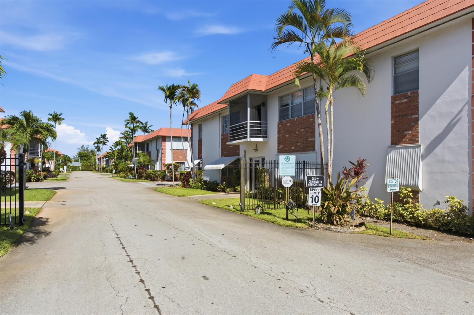 A paved road leads past two-story apartment buildings with orange roofs and palm trees — 3550 NW 8th Avenue # 812, Pompano Beach FL 33064, POMPANO BEACH, FL