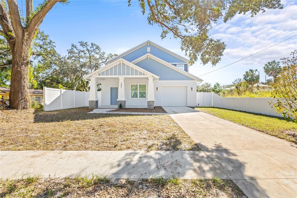 A light blue house with a front porch, garage, and white vinyl fencing — 3005 E 17TH AVENUE, TAMPA, FL