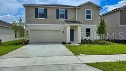 A two-story suburban house with a beige exterior, a two-car garage, and a concrete driveway — 1322 BELLE ISLE LANE, DAYTONA BEACH, FL
