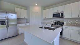 A modern kitchen features white cabinets, stainless steel appliances, and a central island with sink — 1322 BELLE ISLE LANE, DAYTONA BEACH, FL