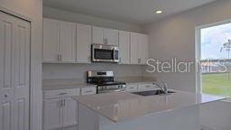 A modern kitchen features white cabinets, stainless steel appliances, and a quartz-topped island — 1322 BELLE ISLE LANE, DAYTONA BEACH, FL
