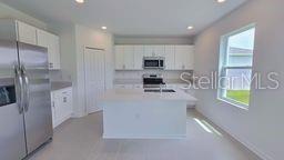 A modern kitchen features white cabinets, stainless steel appliances, and a central island — 1322 BELLE ISLE LANE, DAYTONA BEACH, FL