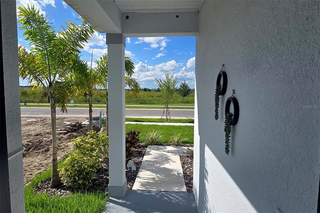 A view from a covered porch looking out toward a street and open field — 5539 MADDIE DRIVE, HAINES CITY, FL