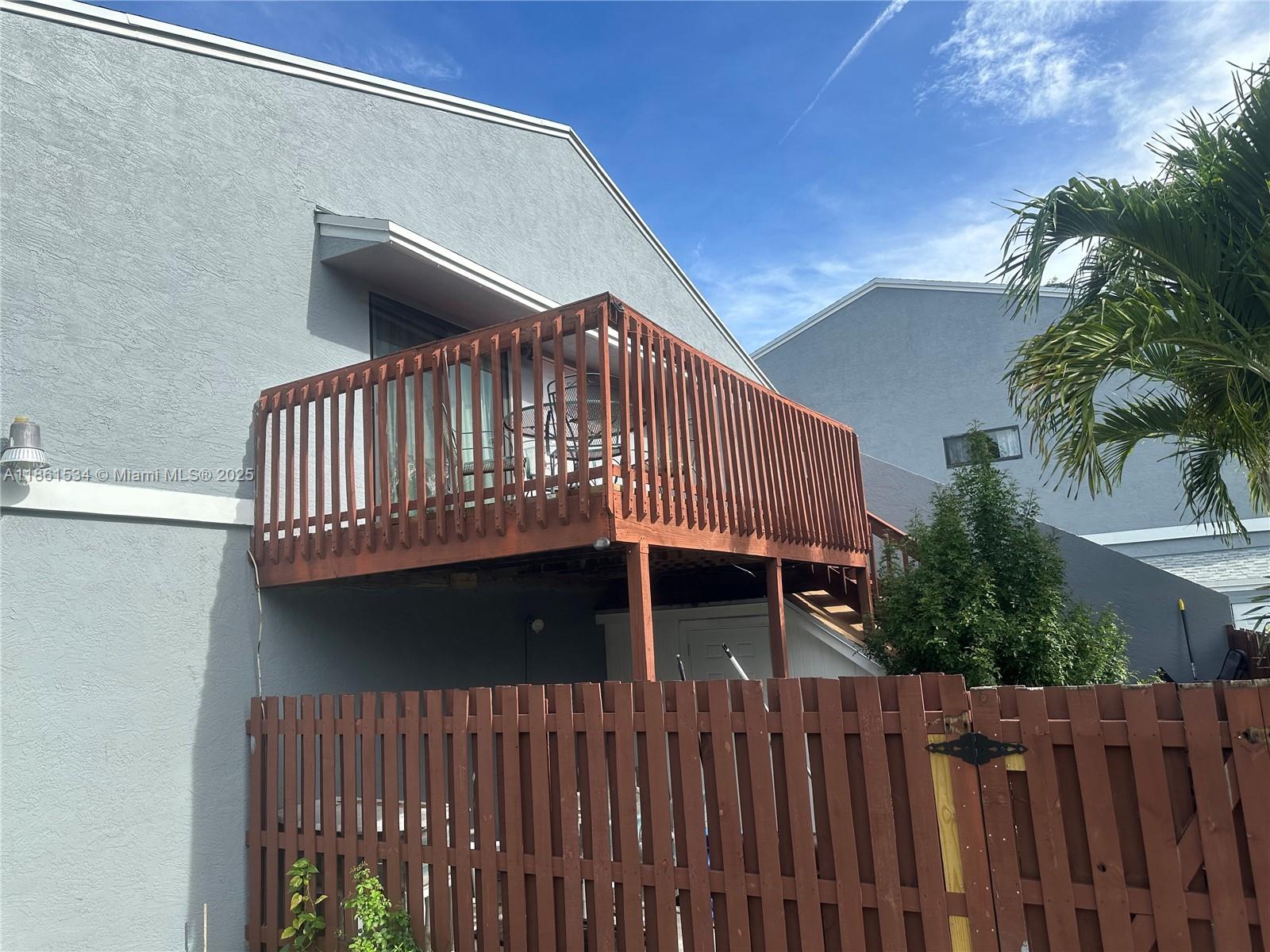 A wooden deck with a railing is attached to the second story of a gray building — 22 Crossings Cir, Boynton Beach FL 33435, BOYNTON BEACH, FL