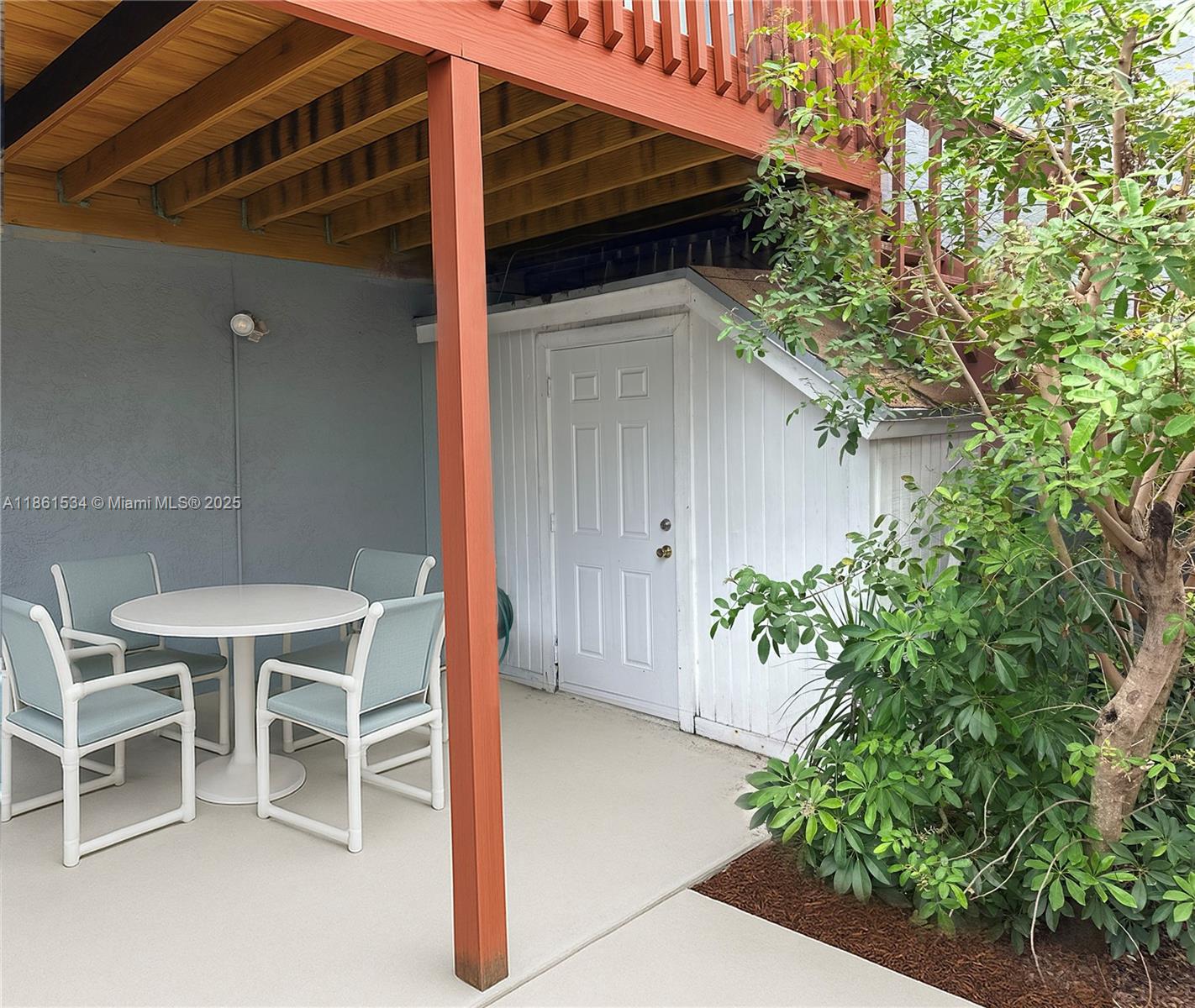 A patio area features a white table with four chairs under a wooden deck structure — 22 Crossings Cir, Boynton Beach FL 33435, BOYNTON BEACH, FL