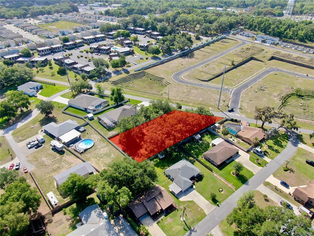 An aerial view shows a rectangular, tree-covered vacant lot highlighted in red within a neighborhood — TBD LOT 1 BENTLEY ROAD, LEESBURG, FL