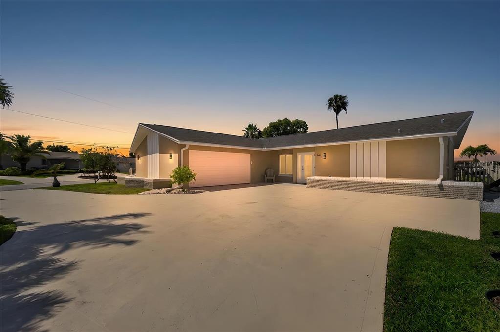 A single-story house with a large concrete driveway and a two-car garage at sunset — 3619 CORSAIR COURT, NEW PORT RICHEY, FL