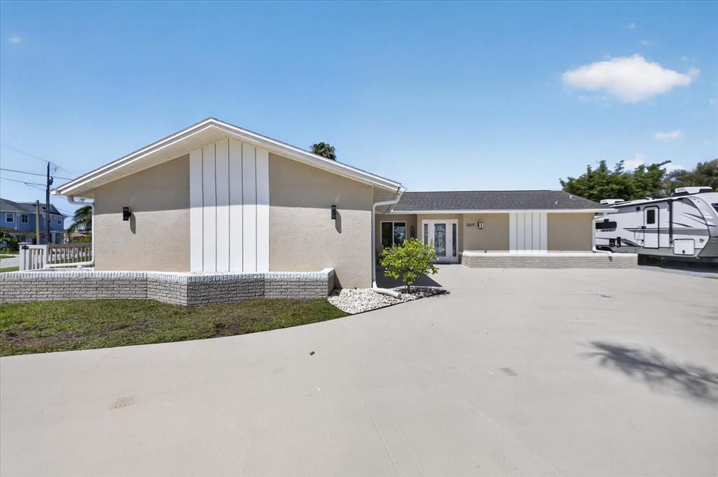 A single-story house with a beige exterior, vertical siding accents, and a large concrete driveway — 3619 CORSAIR COURT, NEW PORT RICHEY, FL