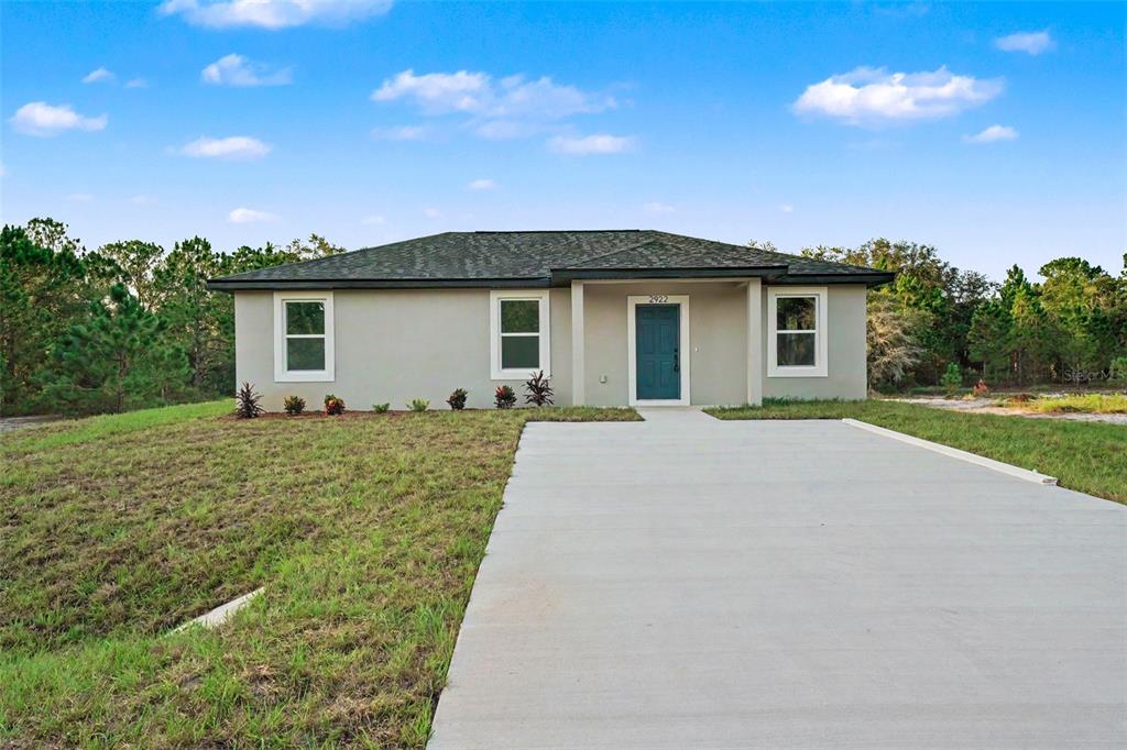 A single-story house with a gray exterior, a dark roof, and a concrete driveway — 2922 W PERRY ROAD, AVON PARK, FL