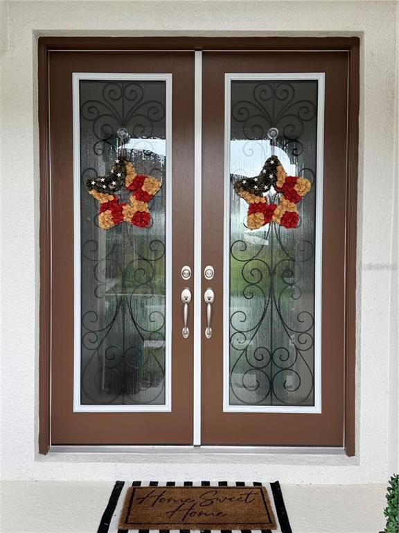 A pair of brown double front doors with glass inserts and star-shaped wreaths — 13150 WELLSPRING DRIVE, LITHIA, FL