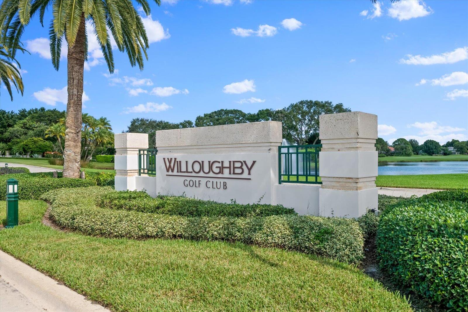 A stone sign for Willoughby Golf Club stands in a landscaped area near a pond — 3498 SE Doubleton Drive, Stuart FL 34997, STUART, FL