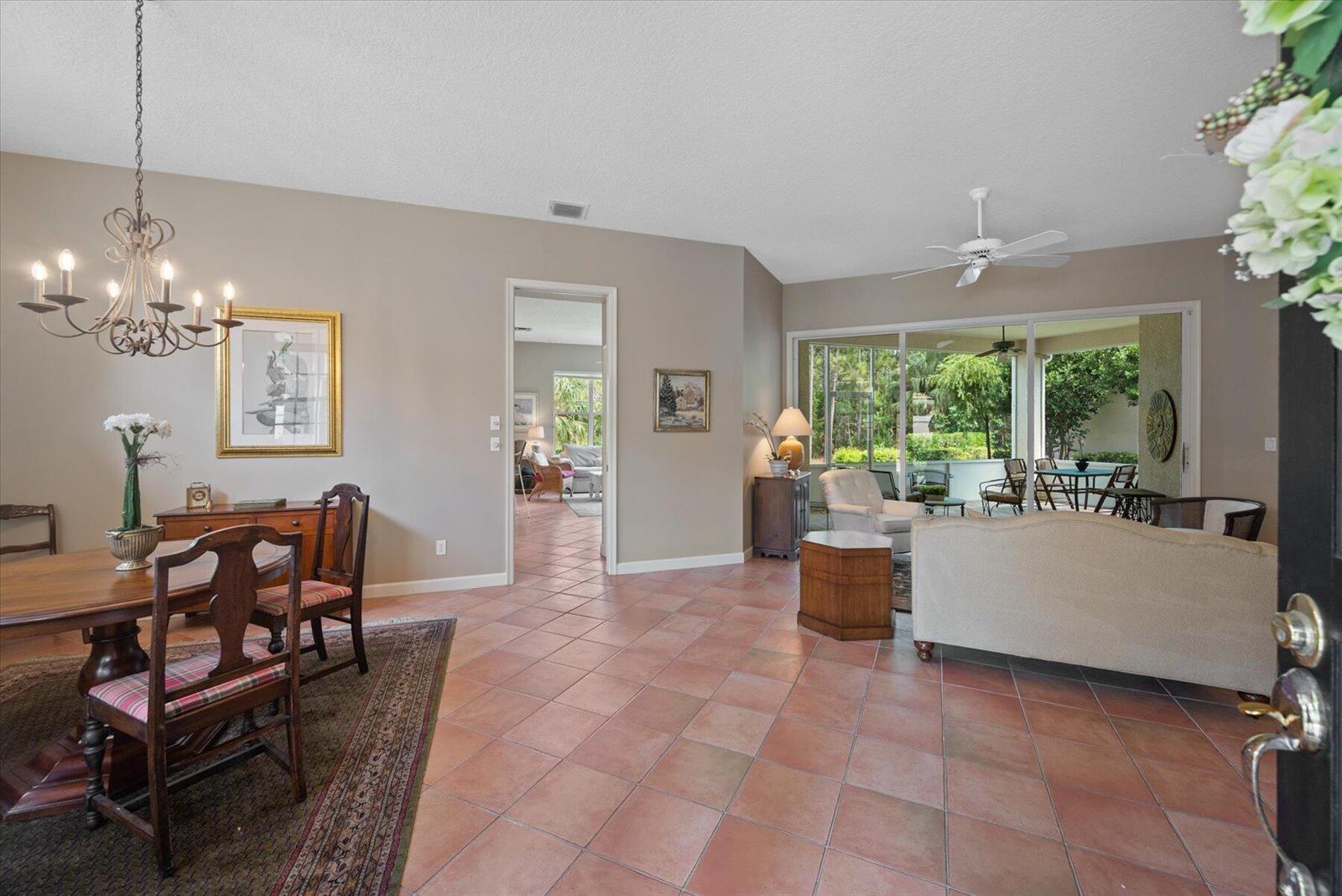 A dining area and living room feature tile floors, a ceiling fan, and sliding glass doors — 3498 SE Doubleton Drive, Stuart FL 34997, STUART, FL