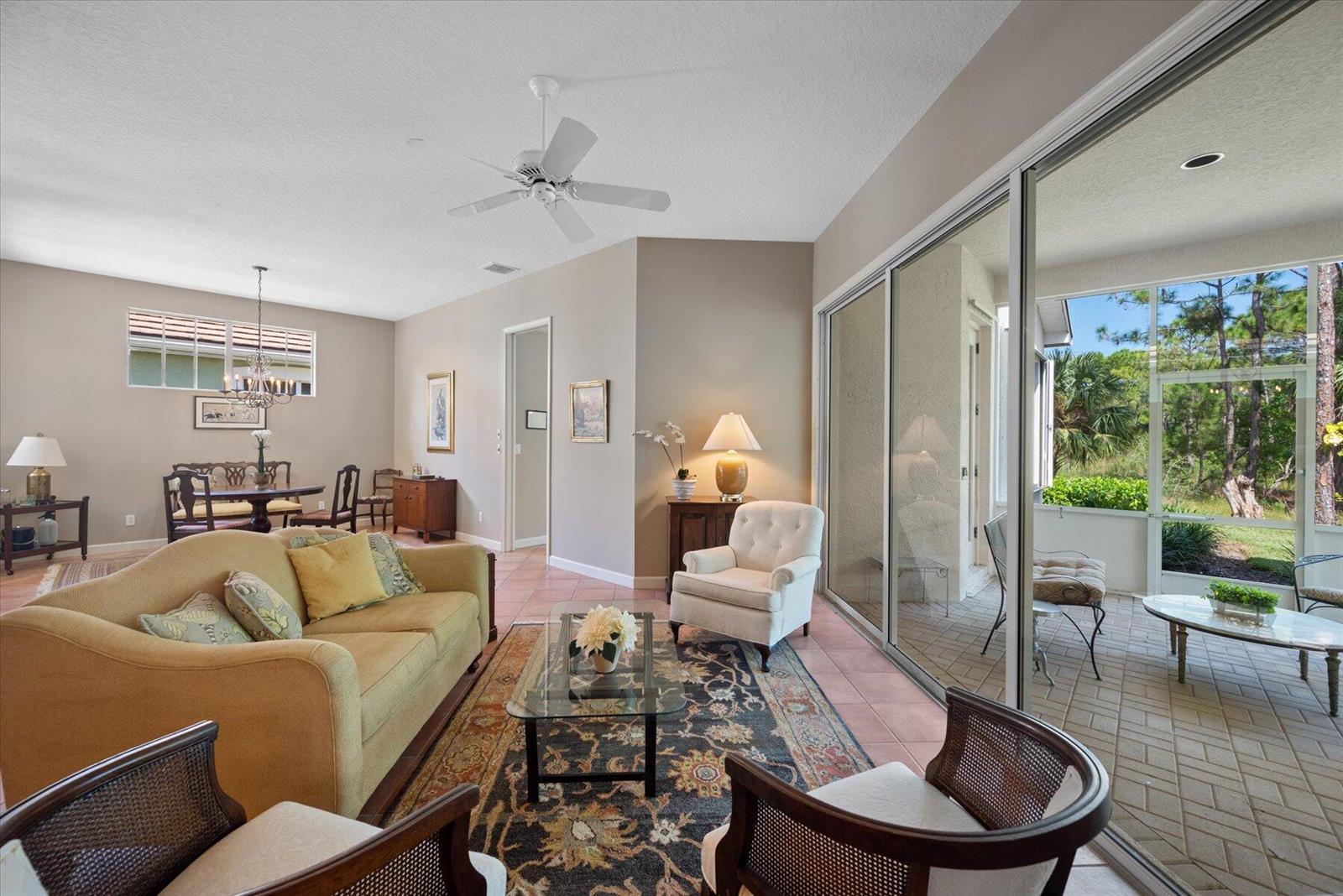 A living room with a sofa, armchairs, and sliding glass doors opening to a screened patio — 3498 SE Doubleton Drive, Stuart FL 34997, STUART, FL