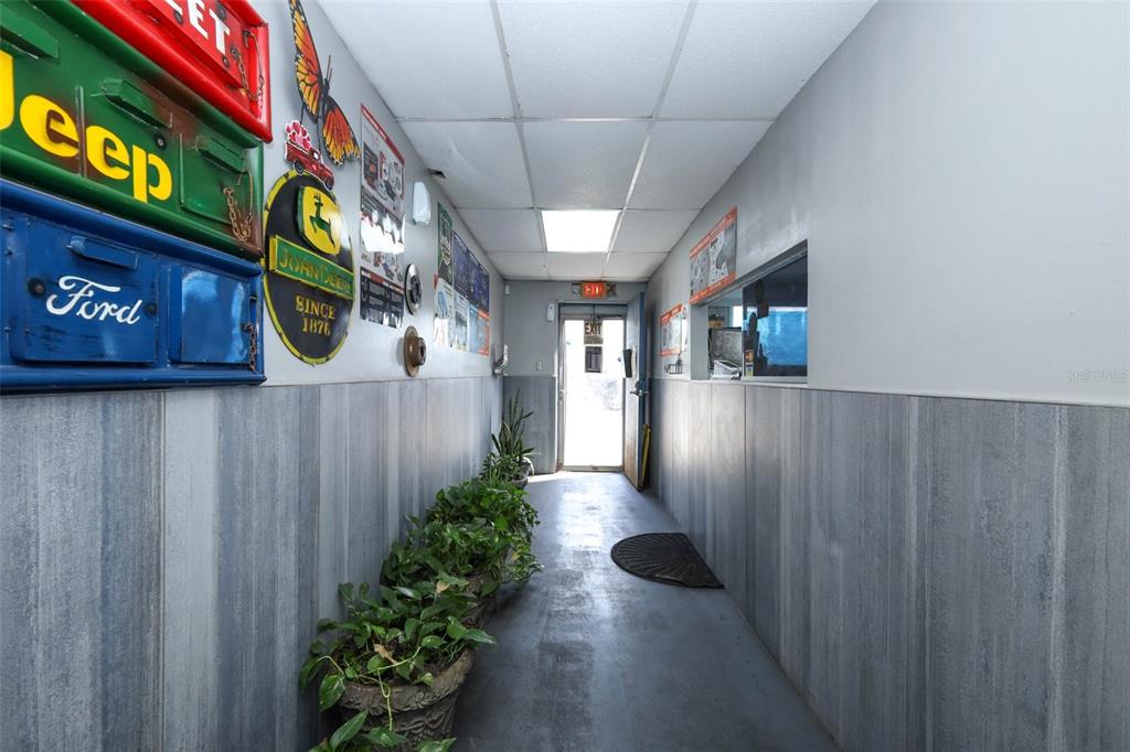 A narrow hallway features gray wainscoting, potted plants, and various automotive signs on the wall — 4070 S GOLDENROD ROAD, ORLANDO, FL