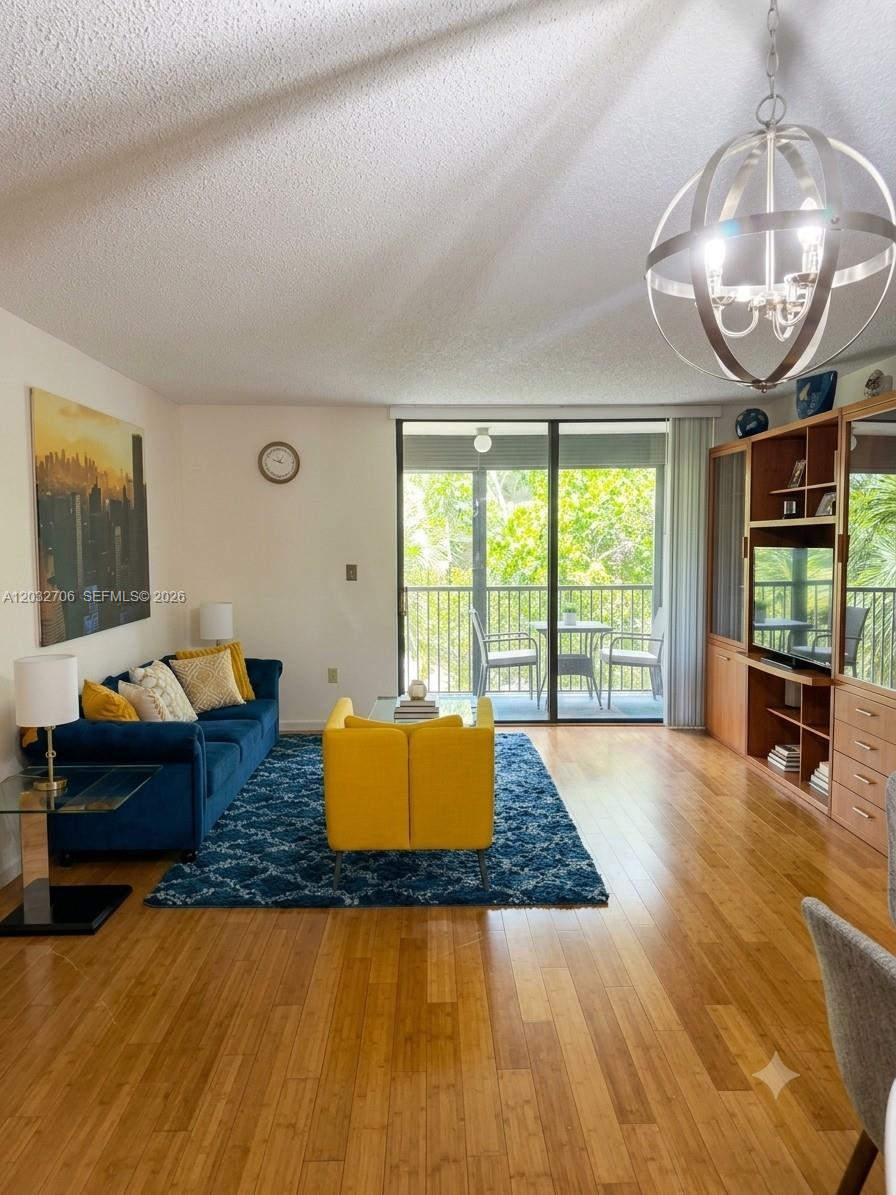 A living room features a blue sofa, yellow armchair, wood flooring, and a large chandelier — 5570 NW 44th St # 308A, Lauderhill FL 33319, LAUDERHILL, FL