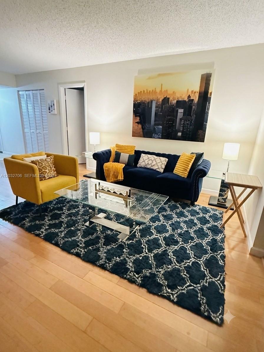A living room features a navy blue tufted sofa, yellow armchair, glass coffee table, and rug — 5570 NW 44th St # 308A, Lauderhill FL 33319, LAUDERHILL, FL