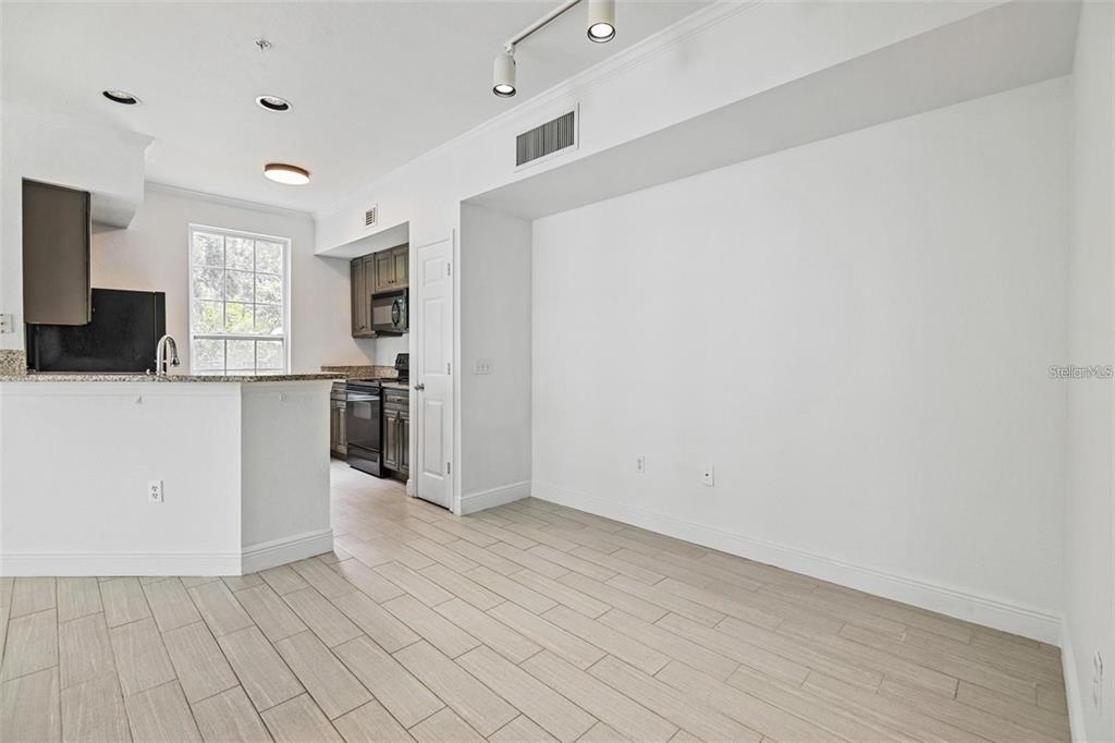 A kitchen with dark cabinets and a breakfast bar opens into an empty dining area — 5571 ROSEHILL ROAD UNIT 104, SARASOTA, FL
