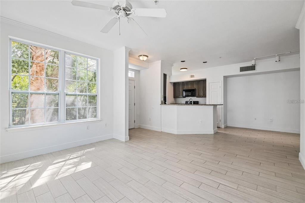 A bright living area with light tile flooring, a ceiling fan, and an open kitchen — 5571 ROSEHILL ROAD UNIT 104, SARASOTA, FL