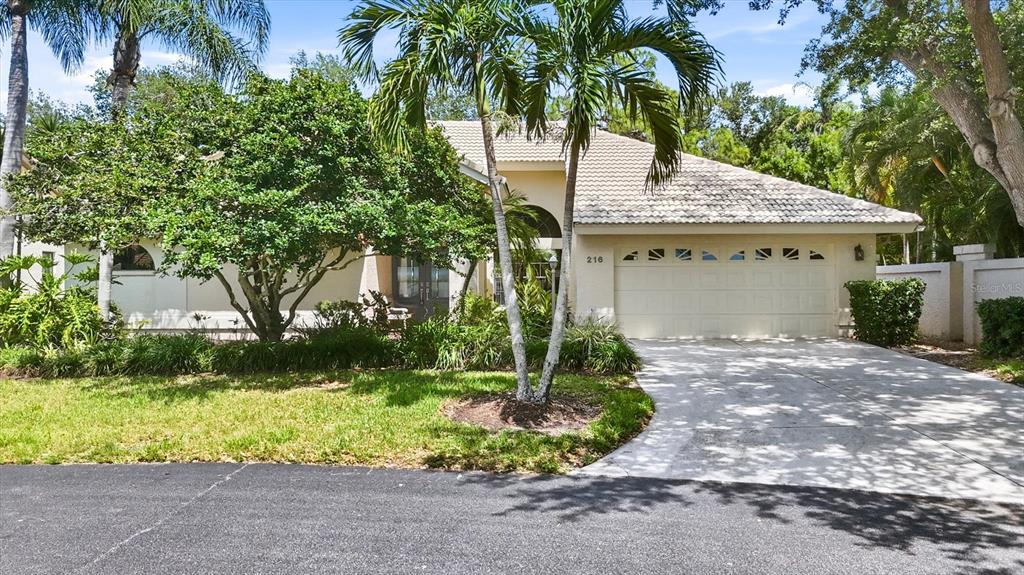 A single-story house with a beige exterior, a tiled roof, and a two-car garage — 216 CARRIAGE HOUSE LANE UNIT 216, NOKOMIS, FL
