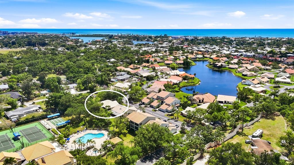 An aerial view shows a residential neighborhood with a lake, tennis courts, and a pool — 216 CARRIAGE HOUSE LANE UNIT 216, NOKOMIS, FL